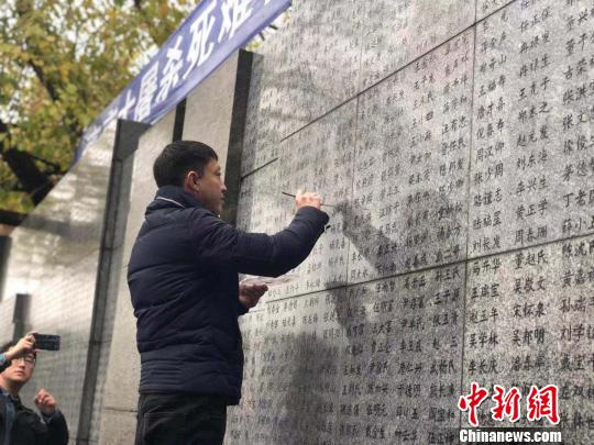 10日晨，下著小雨。南京大屠殺幸存者、死難者遺屬、學(xué)生們依次描寫名字，祭悼南京大屠殺遇難同胞。淡淡的墨汁摻著雨水，滲入了刻在紀(jì)念館灰色厚重石壁上的黑色名字中?！≈鞎苑f 攝